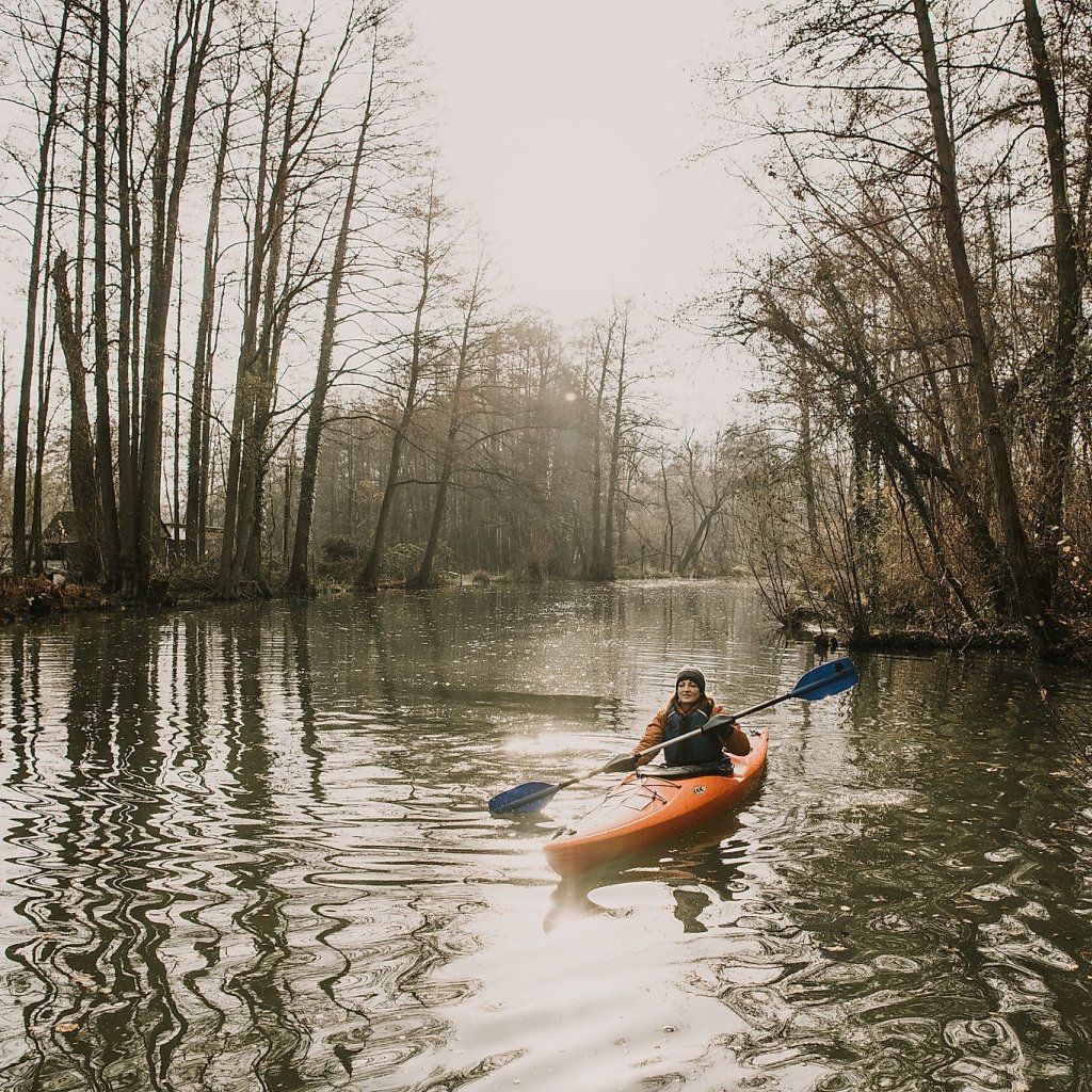 Kanutour im Spreewald im Winter Person in einem Kanu vor winterlicher Landschaft und kahlen Bäumen